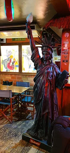 Réplica de la Estatua de la Libertad dentro del Rolling Rock, junto a las mesas de madera