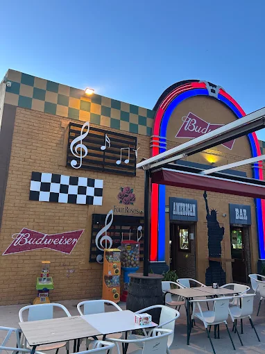 Entrada del Rolling Rock American Bar al atardecer, con el damero y las notas musicales de la fachada