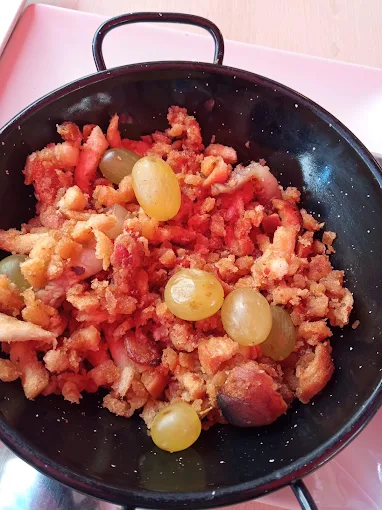 Sartén de migas manchegas con torreznos y uvas, plato de temporada